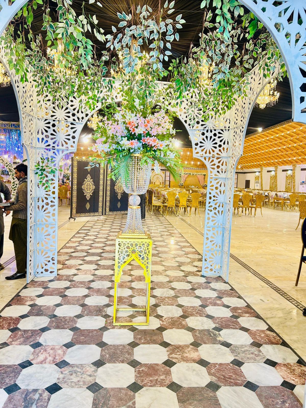 Floral Aisle Walkway — Lattice arches with lush hanging greenery leading toward the stage.
